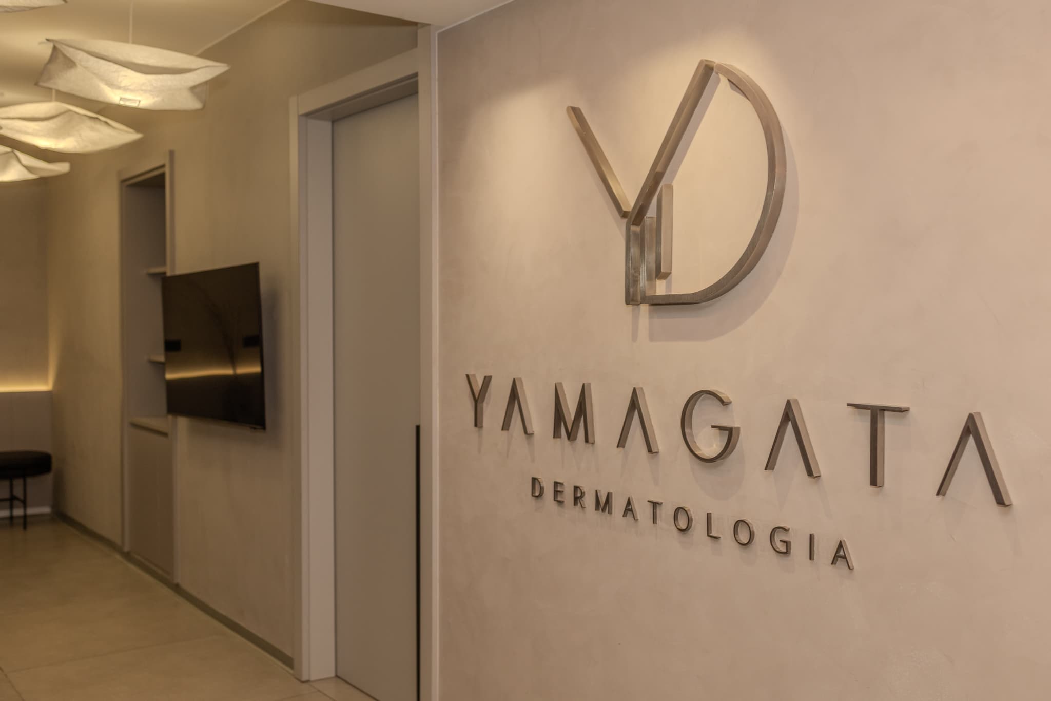 Recepção da Yamagata Dermatologia, com o logotipo da clínica na parede