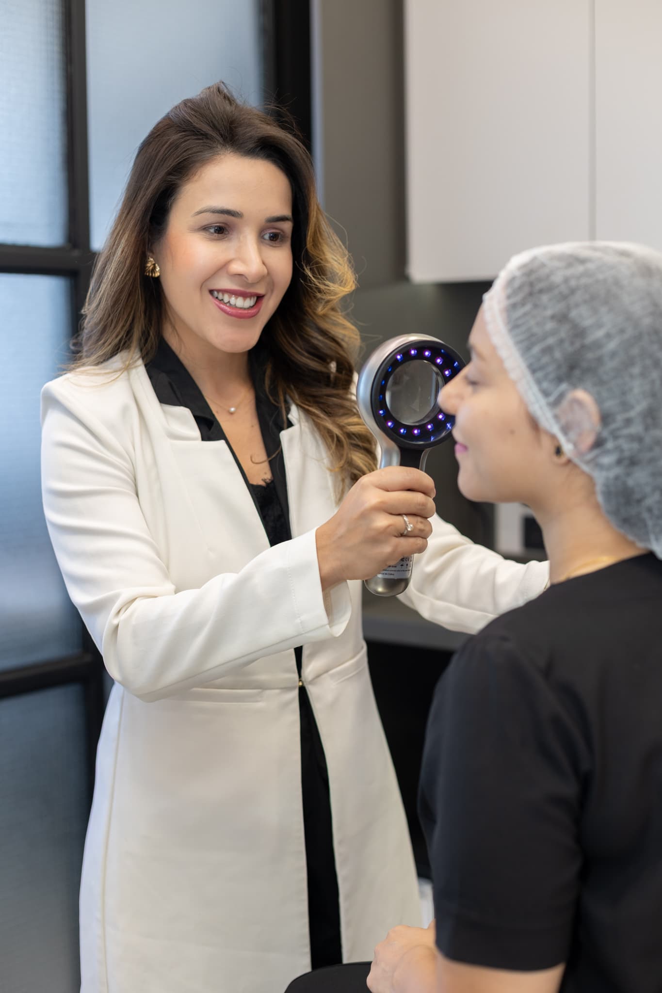 Dermatologista examina a pele do rosto de uma paciente com um dermatoscópio