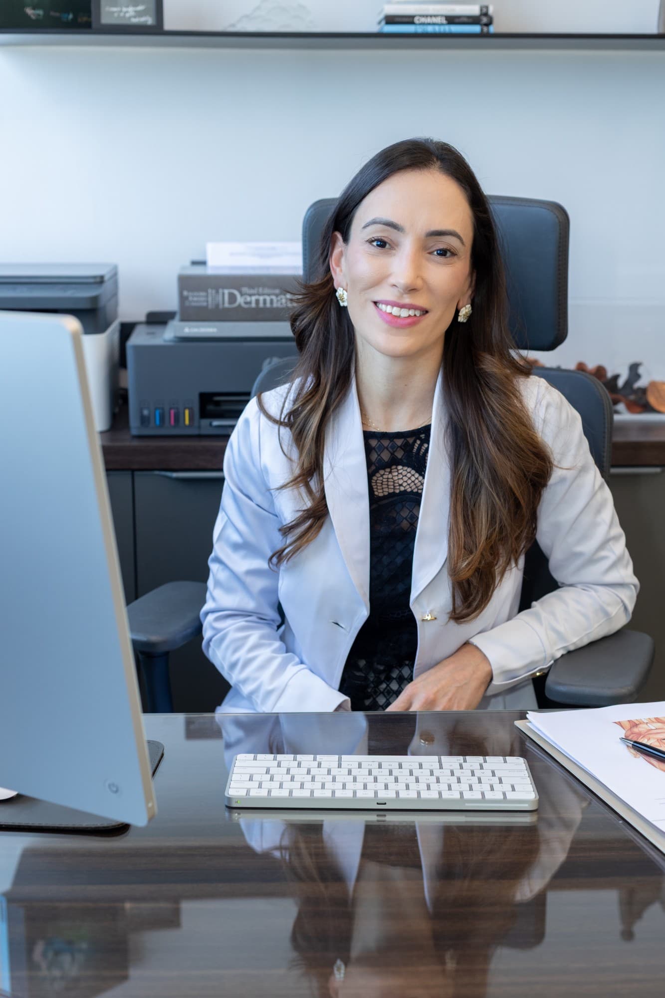 Dra. Vivian Santos, médica dermatologista, sentada à mesa do consultório na Yamagata Dermatologia