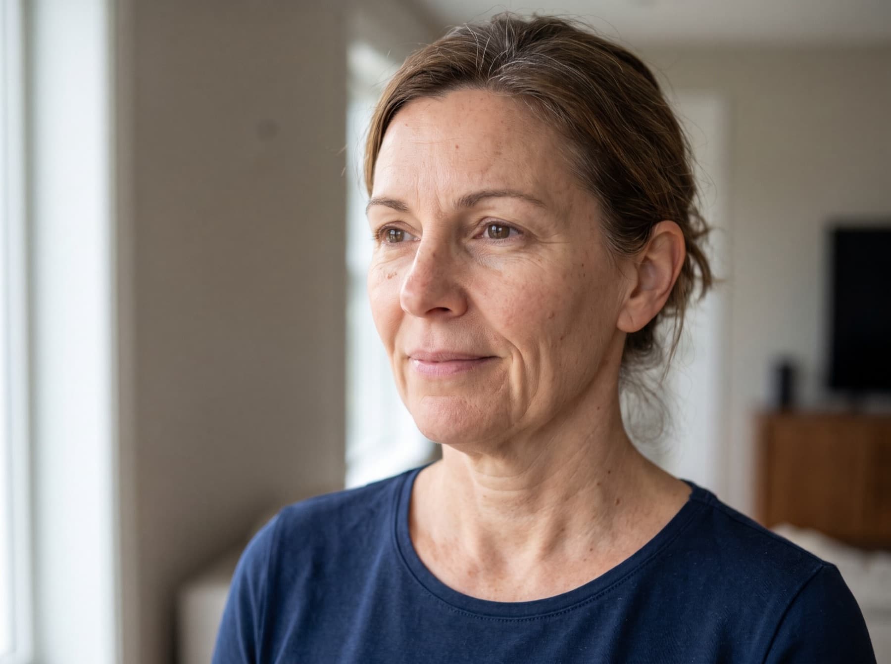 Mulher de meia-idade, de perfil, com rosto mais fino, sulcos marcados e pele do pescoço com flacidez