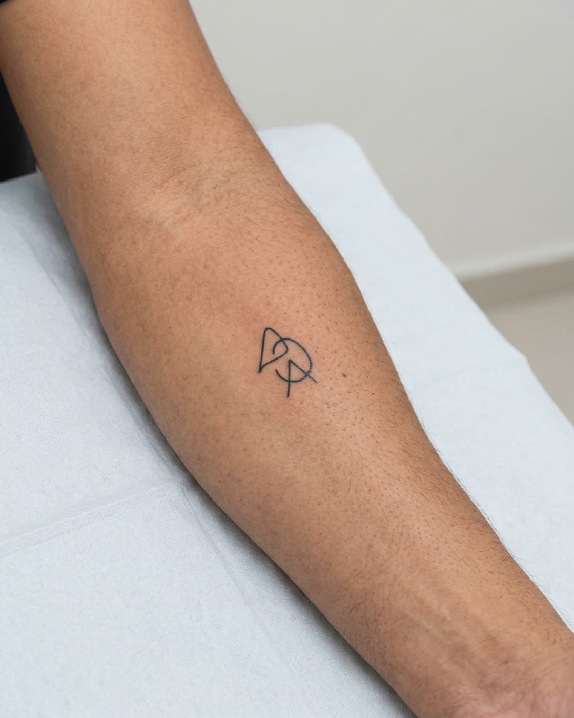 Antebraço com uma pequena tatuagem preta