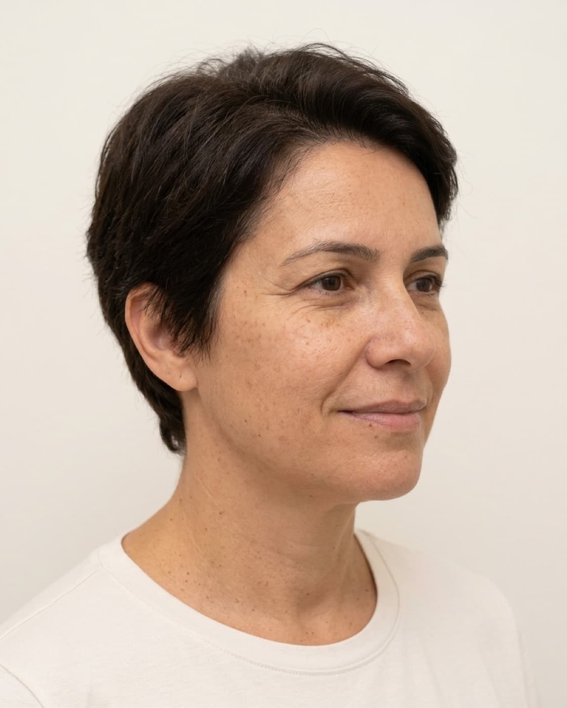 Mulher madura sorrindo levemente, com rugas na testa e ao redor dos olhos