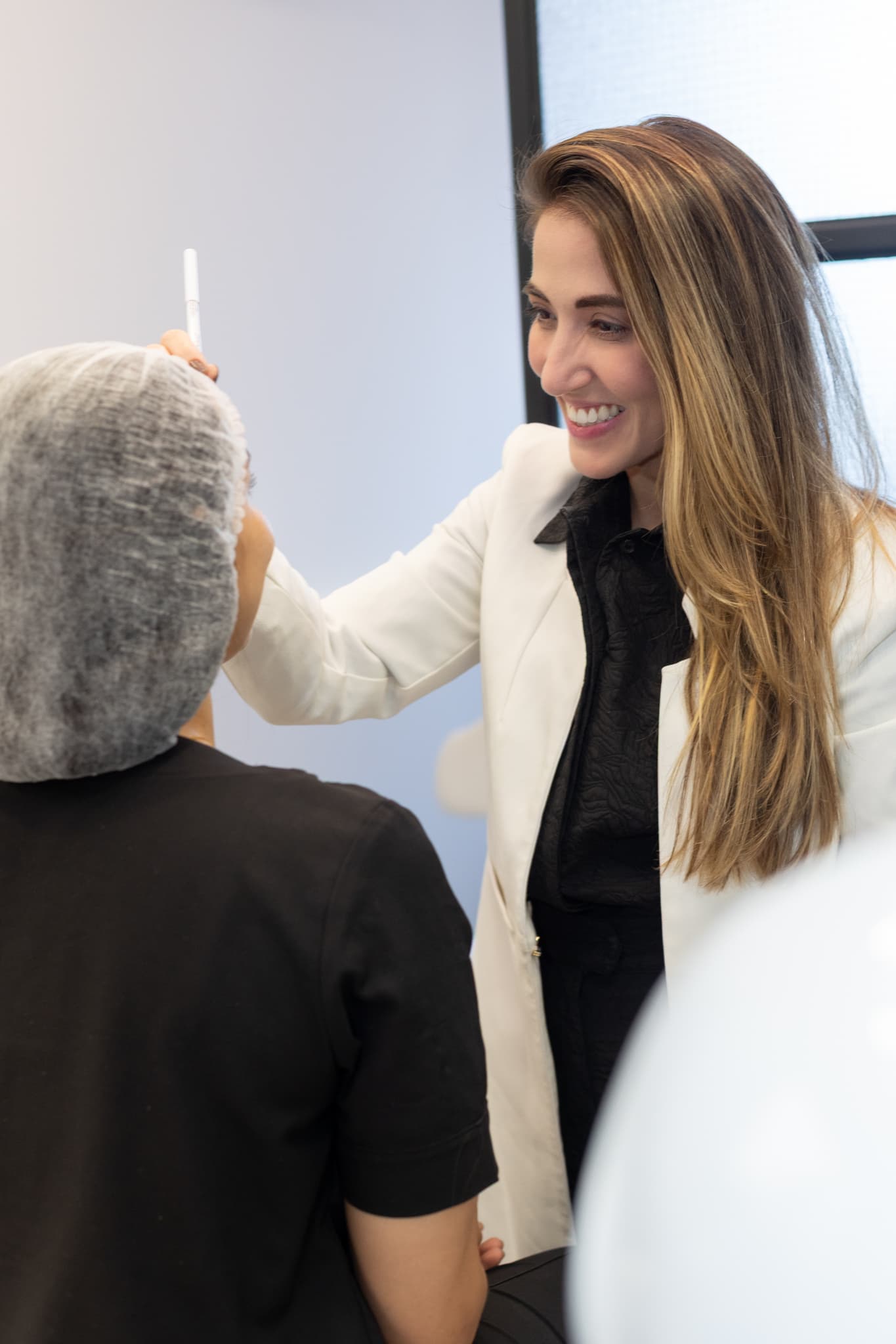 Dermatologista marca pontos na testa de uma paciente para o planejamento da aplicação